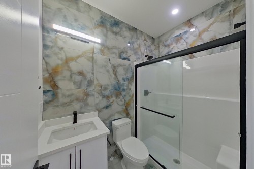 Bathroom featuring an elegant vanity with a single sink and black faucet, a toilet, and a glass-enclosed shower with a black frame - 8425 Mayday Link Link, Edmonton, AB - Indoor Photo Showing Bathroom