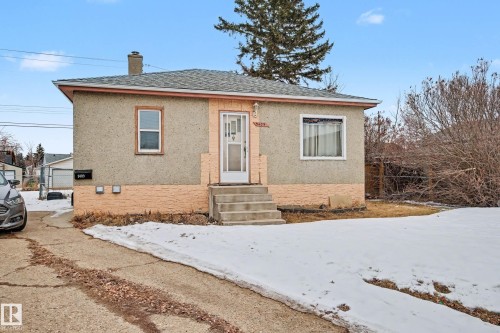 The property features an exterior with textured siding and brick detailing, a front entrance with concrete steps, and a paved driveway - 9409 154 Street, Edmonton, AB - Outdoor