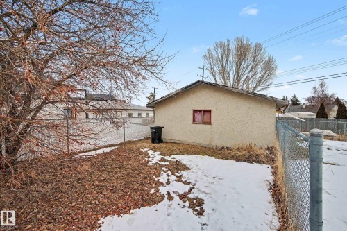 This property features a structure with stucco siding and a small window with red curtains - 9409 154 Street, Edmonton, AB - Outdoor