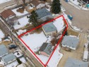 Aerial view of the property, featuring a main residence with a gray roof and light-colored siding, a detached garage with a pink and gray roof, and a large lot partially covered in snow - 9409 154 Street, Edmonton, AB  - Outdoor With View 