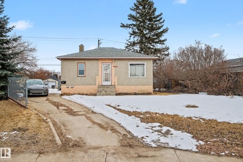 The property features a stucco exterior, a sloped shingled roof, and a front yard with partial snow cover - 9409 154 Street, Edmonton, AB - Outdoor