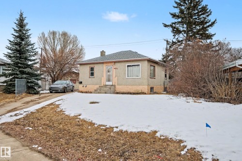 The property features a single-story dwelling with a grey shingled roof, light-colored siding, and a partial brick foundation - 9409 154 Street, Edmonton, AB - Outdoor