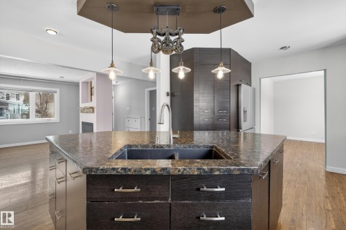 The kitchen features a spacious island with a dark stone countertop and an integrated sink, complemented by pendant lighting - 3613 113 Avenue, Edmonton, AB - Indoor Photo Showing Kitchen With Double Sink With Upgraded Kitchen