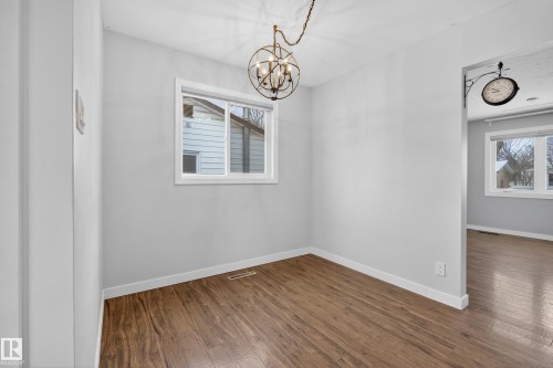 This room features hardwood floors, a window with white trim, and a decorative ceiling light fixture - 3613 113 Avenue, Edmonton, AB - Indoor Photo Showing Other Room