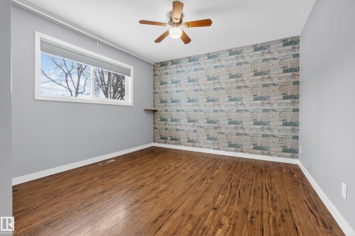 The property features hardwood style flooring, a window with a white frame, and a ceiling fan with light fixture - 3613 113 Avenue, Edmonton, AB - Indoor Photo Showing Other Room