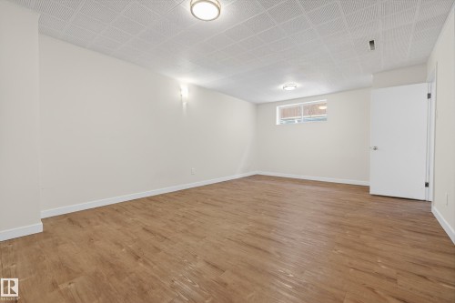 Spacious room featuring wood-look flooring, light-colored walls, and a window providing natural light - 3613 113 Avenue, Edmonton, AB - Indoor Photo Showing Other Room