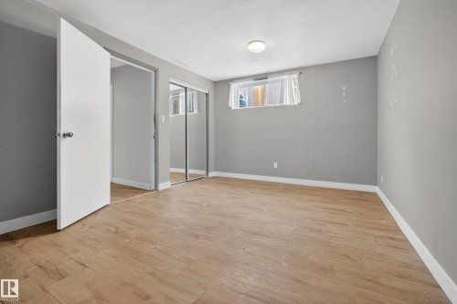 This room features light wood-look flooring, neutral grey walls, and a window with a white curtain - 3613 113 Avenue, Edmonton, AB - Indoor Photo Showing Other Room