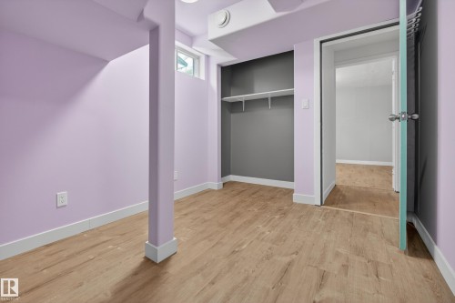 This room features light wood-style flooring, a built-in shelving unit with two shelves, and a window providing natural light - 3613 113 Avenue, Edmonton, AB - Indoor Photo Showing Other Room