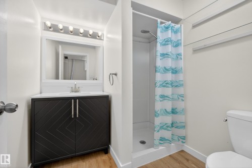 The bathroom features a vanity with a dark wood finish and white countertop, a shower, and a toilet - 3613 113 Avenue, Edmonton, AB - Indoor Photo Showing Bathroom
