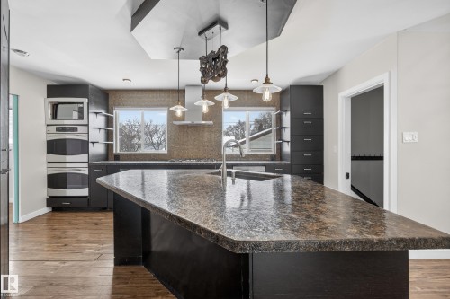 Kitchen featuring a large island with a speckled countertop, dark cabinetry, and hardwood floors - 3613 113 Avenue, Edmonton, AB - Indoor Photo Showing Kitchen With Upgraded Kitchen