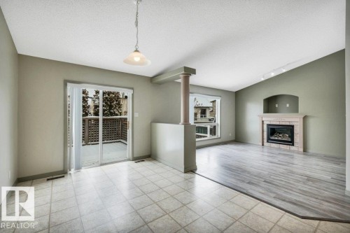 The living area features a fireplace with a mantel, a window, and wood-style flooring - 902 Graham Wynd, Edmonton, AB - Indoor With Fireplace