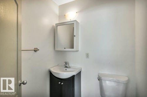 The bathroom features a pedestal vanity with a single basin sink, a wall-mounted medicine cabinet, and a toilet - 902 Graham Wynd, Edmonton, AB - Indoor Photo Showing Bathroom