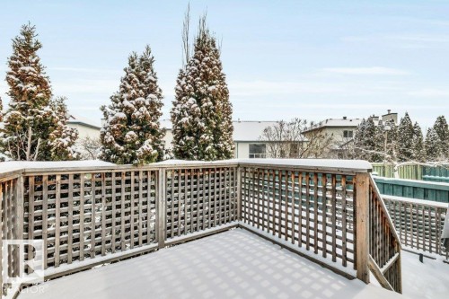 The property includes a wooden deck with a lattice railing, offering a view of surrounding mature evergreen trees - 902 Graham Wynd, Edmonton, AB - Outdoor