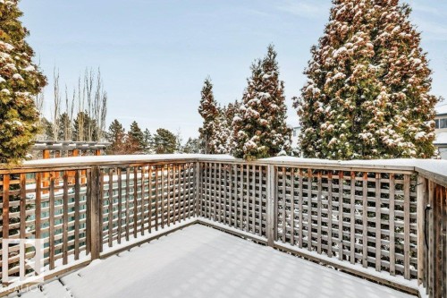The property features a private outdoor deck with a wooden lattice railing, offering views of surrounding evergreen trees - 902 Graham Wynd, Edmonton, AB - Outdoor