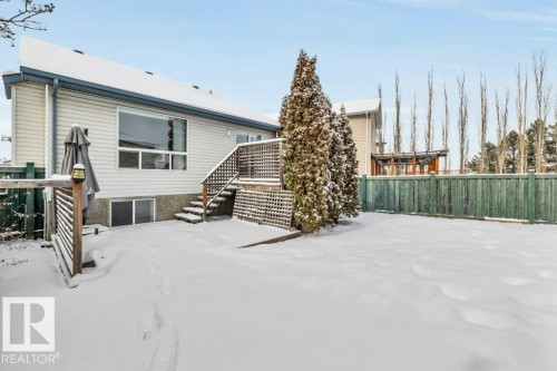 The property features a spacious rear yard with a wooden fence and mature evergreen trees - 902 Graham Wynd, Edmonton, AB - Outdoor