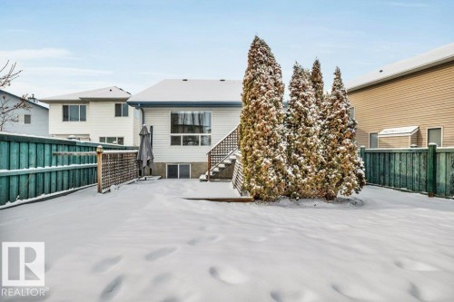The property features a fenced yard with a patio area and mature evergreen trees - 902 Graham Wynd, Edmonton, AB - Outdoor