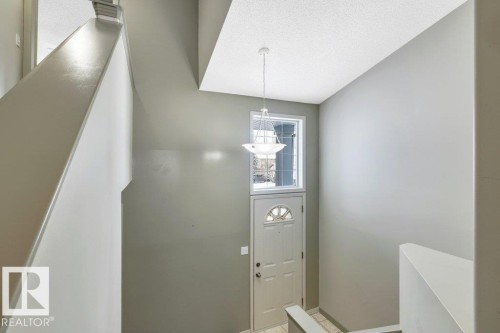 Entryway featuring a front door with a decorative glass insert, an overhead window, and a hanging light fixture - 902 Graham Wynd, Edmonton, AB - Indoor Photo Showing Other Room