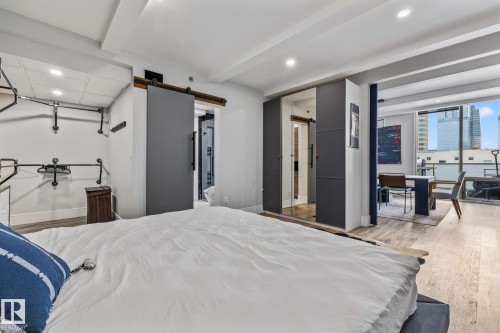 The property features light-colored hardwood flooring, recessed lighting, and a modern barn door - 314 10309 107 Street, Edmonton, AB - Indoor Photo Showing Bedroom