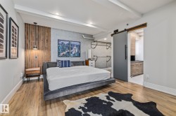 Primary bedroom featuring hardwood floors, a barn door, and a textured accent wall - 