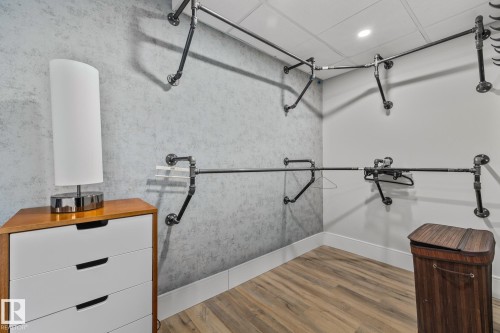 The property features a closet with textured walls, industrial-style clothing racks, and wood-look flooring - 314 10309 107 Street, Edmonton, AB - Indoor Photo Showing Garage
