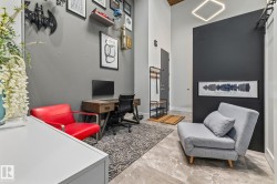 This versatile space features a high ceiling with a geometric light fixture, grey walls, and grey tiled flooring - 