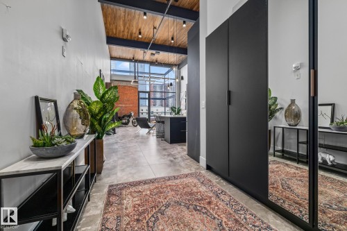 The property features an entryway with high ceilings, exposed wooden beams, and track lighting - 314 10309 107 Street, Edmonton, AB - Indoor Photo Showing Other Room