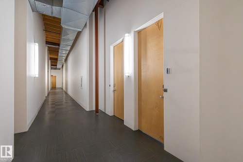 The property features a hallway with dark grey floor tiles, light-colored walls, and wooden doors - 314 10309 107 Street, Edmonton, AB - Indoor Photo Showing Other Room