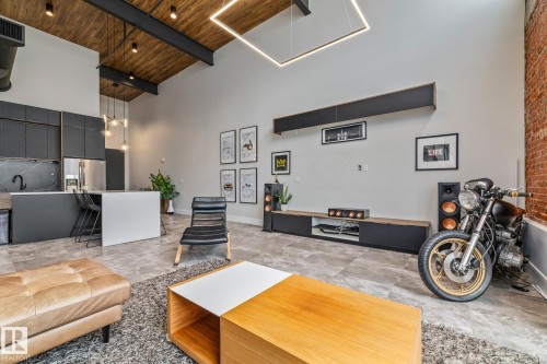 This property features high ceilings with exposed wooden beams and dark metal accents - 314 10309 107 Street, Edmonton, AB - Indoor