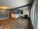 Unfurnished living room featuring a fireplace, vaulted ceiling, dark wood-type flooring, a textured ceiling, and a wainscoted wall - 15016 80 Street, Edmonton, AB  - Indoor Photo Showing Other Room 