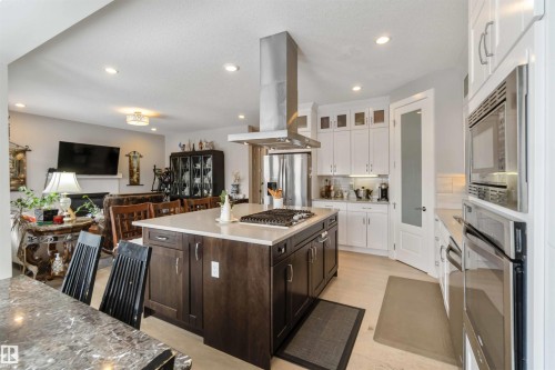 The property features an open concept kitchen with a large island, stainless steel appliances, and white cabinetry - 4 Lakeshore Cove, Beaumont, AB 
