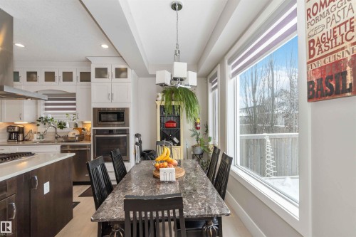 This dining area features a large window, a dining table with chairs, and a contemporary light fixture - 4 Lakeshore Cove, Beaumont, AB 
