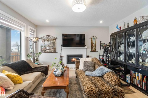 The living room features a fireplace with a mantel, recessed lighting, and a large window providing views of the outdoors - 4 Lakeshore Cove, Beaumont, AB 