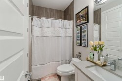 This bathroom features a shower area with tiled walls, a vanity with a rectangular sink, and a large mirror - 