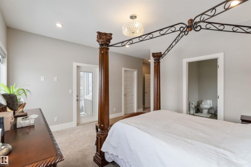 The property features a spacious room with light gray walls, carpet flooring, and a decorative ceiling light fixture - 4 Lakeshore Cove, Beaumont, AB 