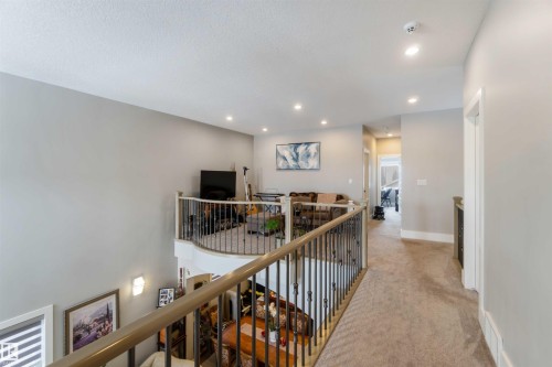A spacious loft area with recessed lighting, light-colored carpeting, and a wrought iron railing overlooking the lower level - 4 Lakeshore Cove, Beaumont, AB 