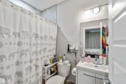 Bathroom featuring a vanity with a white sink, a toilet, and a shower with a patterned curtain - 