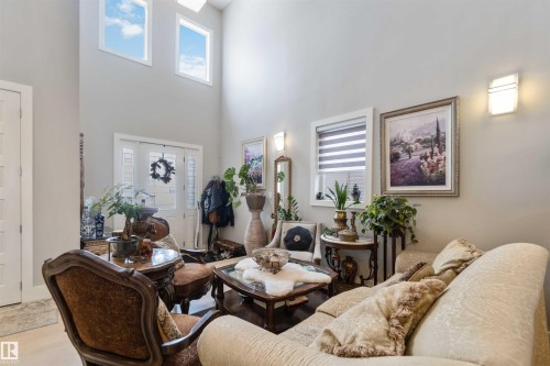 The living space features high ceilings with upper windows and wall sconces, creating a bright and inviting atmosphere - 4 Lakeshore Cove, Beaumont, AB 