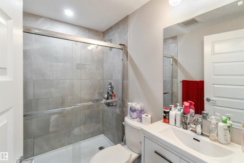 The bathroom features a shower with a clear glass enclosure and light grey tiled walls - 4 Lakeshore Cove, Beaumont, AB 
