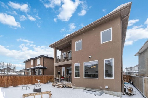 The property features a brown stucco exterior with an angled roofline, multiple windows, and a two-story covered patio with railings - 4 Lakeshore Cove, Beaumont, AB 