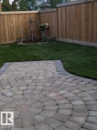 The property features a well-maintained lawn and a paved patio with a circular design - 