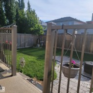The property features a fenced yard with a lawn, mature trees, and a paved patio area - 