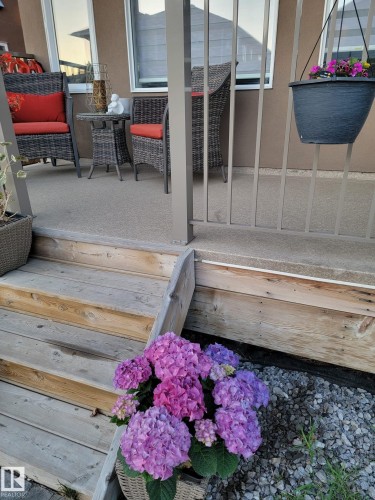 This property features a patio with an exterior wall, railings, and wood steps - 4 Lakeshore Cove, Beaumont, AB 
