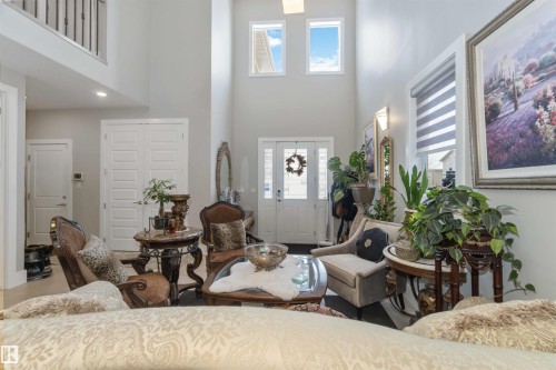 The property features high ceilings, a grand entryway with a transom window and sidelights, and a second-story interior balcony overlooking the main living area - 4 Lakeshore Cove, Beaumont, AB 