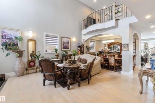 The property features high ceilings, light-toned flooring, and a second-story balcony with metal railings overlooking the living area - 4 Lakeshore Cove, Beaumont, AB 