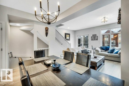 The property features an open-concept living space with light-toned flooring, a staircase with dark metal railings, and large windows providing natural light - 99 1010 Rabbit Hill Road, Edmonton, AB - Indoor