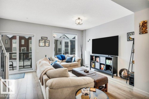 The property features light-colored flooring throughout, a ceiling light fixture, and a large window providing natural light - 99 1010 Rabbit Hill Road, Edmonton, AB - Indoor Photo Showing Living Room