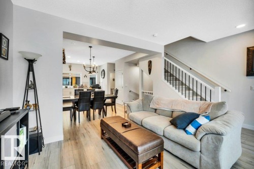 Open concept living and dining areas featuring light-toned flooring, a staircase with white risers and dark balusters, and recessed lighting - 99 1010 Rabbit Hill Road, Edmonton, AB - Indoor Photo Showing Living Room