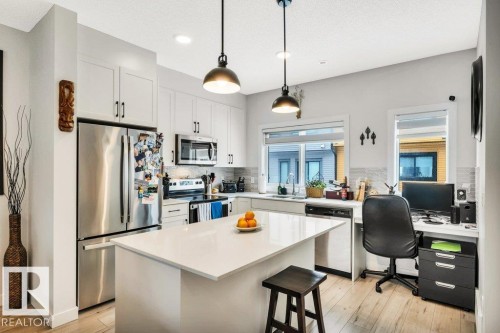 The kitchen features white cabinetry, stainless steel appliances, a center island with a light-colored countertop, and recessed lighting - 99 1010 Rabbit Hill Road, Edmonton, AB - Indoor Photo Showing Kitchen With Upgraded Kitchen