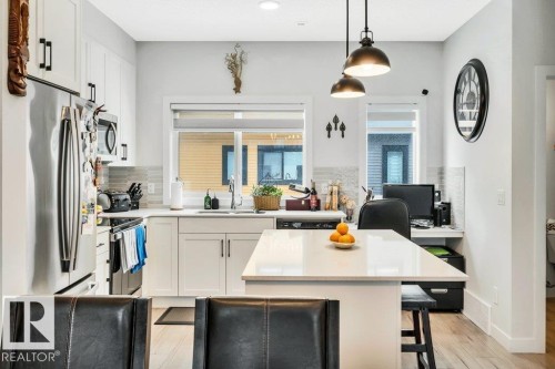 The kitchen features white cabinetry, stainless steel appliances, and a light-colored countertop - 99 1010 Rabbit Hill Road, Edmonton, AB - Indoor