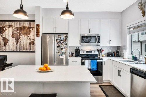 The kitchen features white cabinetry, stainless steel appliances, and a light-colored countertop - 99 1010 Rabbit Hill Road, Edmonton, AB - Indoor Photo Showing Kitchen With Double Sink With Upgraded Kitchen